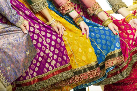 Mehrere Frauen präsentieren ihre Saris. Zu sehen sind Hände, die die bunten Stoffe halten.