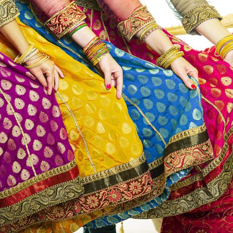 Mehrere Frauen präsentieren ihre Saris. Zu sehen sind Hände, die die bunten Stoffe halten.