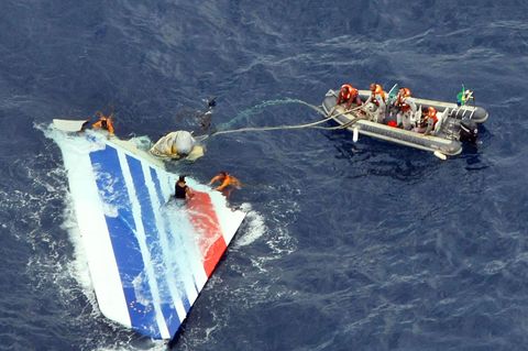 Ein Leitwerk mit dem Logo von Air France schwimmt im Meer, während daneben ein Schlauchboot mit Menschen treibt