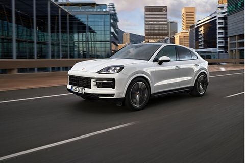 Der neue Porsche Cayenne fährt auf einer Straße durch städtische Umgebung