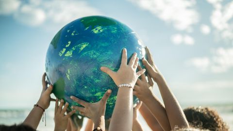 Ein von vielen Händen getragener Globus als Symbolfoto für den Earth Day