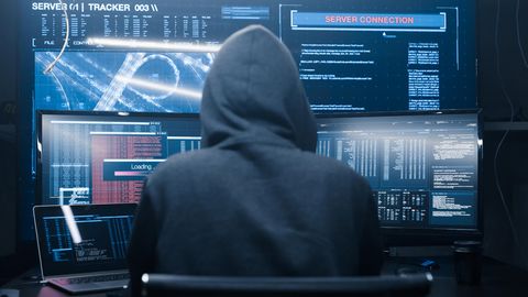Eine Person im Hoodie sitzt vor mehreren Bildschirmen – FBI ermittelt