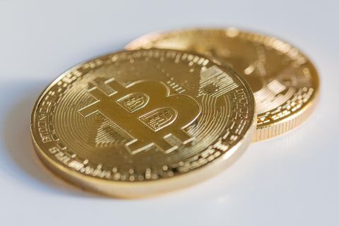 Zwei Bitcoin Münzen liegen auf einem weißen Tisch