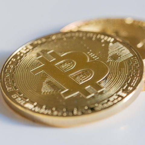 Zwei Bitcoin Münzen liegen auf einem weißen Tisch