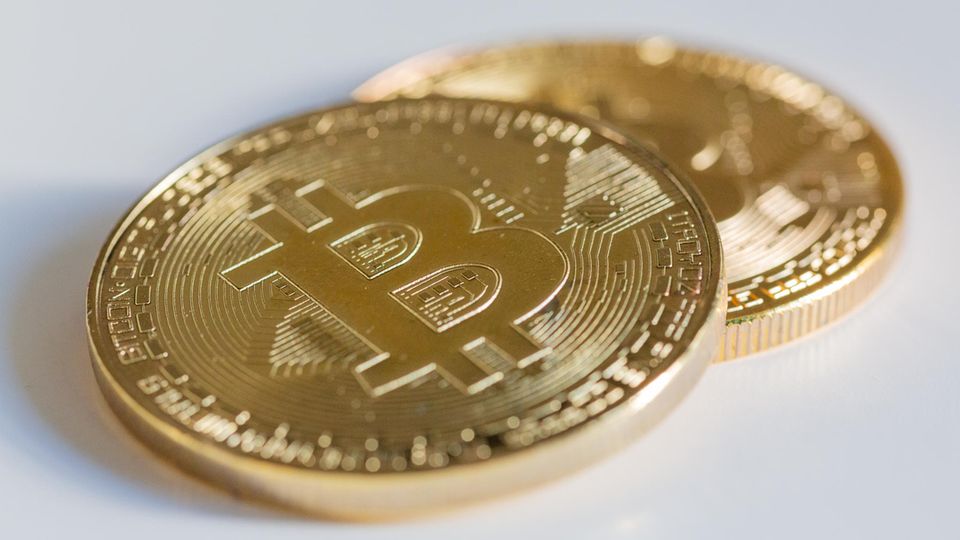 Zwei Bitcoin Münzen liegen auf einem weißen Tisch