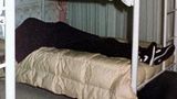 Zwei zugedeckte Tote liegen auf einem Stockbett, sie tragen identische Kleidung und sind mit einem lila Tuch bedeckt