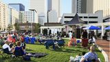 Menschen sitzen in einem Park in Charlotte, im Hintergrund Wolkenkratzer