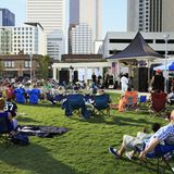 Menschen sitzen in einem Park in Charlotte, im Hintergrund Wolkenkratzer