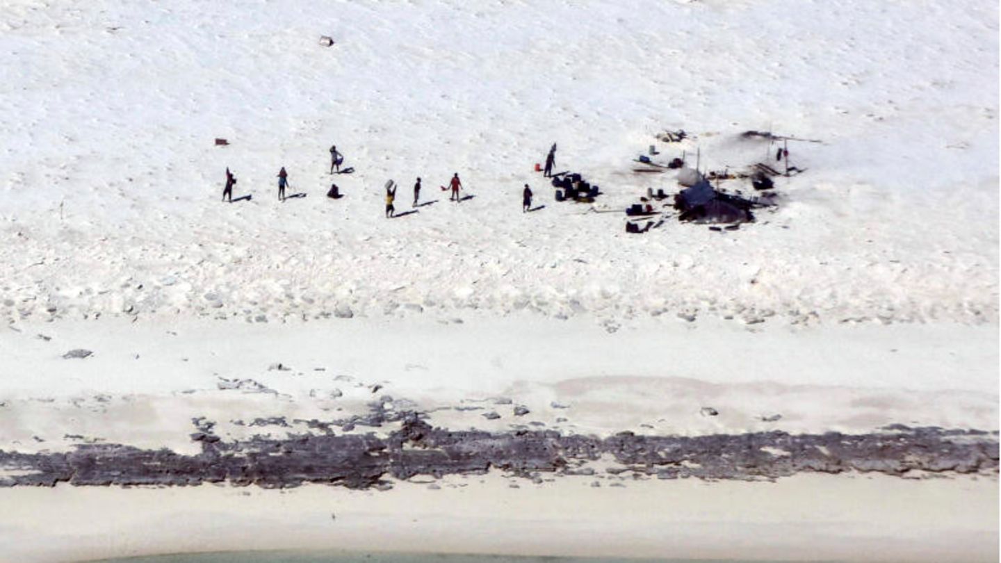Fischer aus Indonesien stehen auf einem Strand auf Bedwell Island