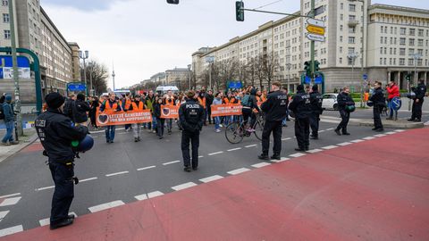 Demo-Teilnehmer stehen Polizisten gegenüber beim Blockademarsch der "Letzten Generation" am Frankfurter Tor in Berlin