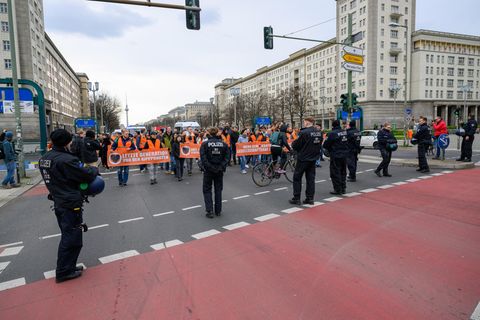 Demo-Teilnehmer stehen Polizisten gegenüber beim Blockademarsch der "Letzten Generation" am Frankfurter Tor in Berlin