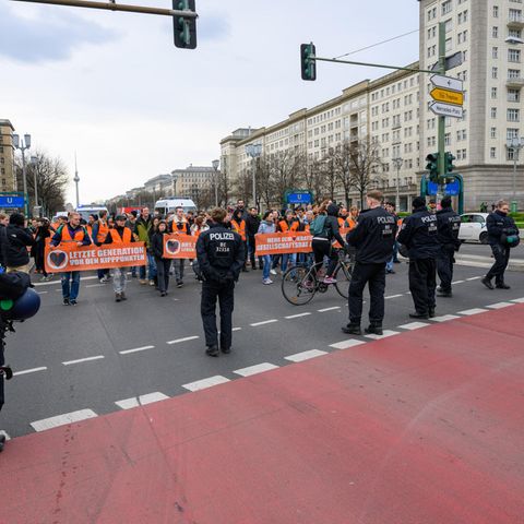 Demo-Teilnehmer stehen Polizisten gegenüber beim Blockademarsch der "Letzten Generation" am Frankfurter Tor in Berlin