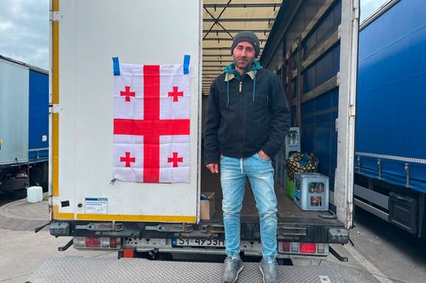 Vasil Agvinishvili steht während des Streiks vor seinem Lkw an dem die Georgische Flagge befestigt ist