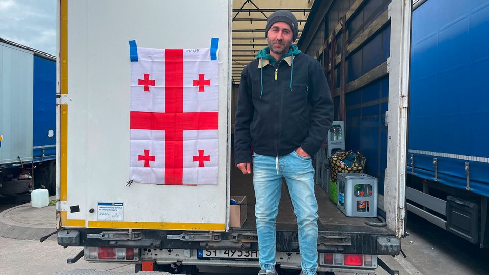 Vasil Agvinishvili steht während des Streiks vor seinem Lkw an dem die Georgische Flagge befestigt ist