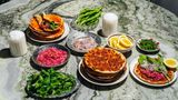 Lahmacun-Express  Zutaten für 18 Stück:  - 345 g Lammhackfleisch, 4 mm (40 % Fett)  - 65 g Biber-Salça  - 65 g Tomaten-Salça  - 5 g Salz  - 6 g gemahlener Kreuzkümmel  - 2 g schwarzer Pfeffer aus der Mühle  - 5 g Pul Biber  - 125 g rote Spitzpaprika (z. B. »Ramiros«)  - 125 g grüne Spitzpaprika (z. B. »Charly«)  - 250 g Tomaten  - 20 g Knoblauch  - 120 g Olivenöl  - 10 g glatte Petersilie, gehackt      Zubereitung:  1. Das Lammhackfleisch mit der Biber- und der Tomaten-Salça sowie allen Gewürzen in einer großen Schüssel gut vermengen. 500 g abwiegen.  2. Die Spitzpaprika entkernen und fein hacken, die Tomaten fein reiben und den Knoblauch schälen und ebenfalls fein reiben. Alles gründlich mit dem Fleisch-Mix vermengen.  3. Dann das Olivenöl und die Petersilie hinzufügen, vermengen und die Masse im Kühlschrank in einem geschlossenen Behälter bis zur Weiterverwendung aufbewahren.      Fertigstellen  - 1 Portion Cüisine-Teig, portioniert à 50 g  Zubereitung:  Vorteig  30 g Wasser  30 g Weißmehl (Weizenmehl; Type 400 oder 405)  1 g frische Hefe (bio)  Alle Zutaten von Hand gut miteinander vermengen. Den Vorteig in einem geschlossenen Behälter 24 Stunden an einem dunklen Ort bei Raumtemperatur gehen lassen.  Hauptteig  61 g Vorteig  355 g lauwarmes Wasser  535 g Weißmehl (Weizenmehl; Type 400 oder 405)  2 g frische Hefe (bio)  10 g Salz  Alle Zutaten außer dem Salz in die Schüssel einer Küchenmaschine geben und mit dem Knethaken auf niedrigster Stufe 8 Minuten kneten lassen. Alternativ das Handrührgerät mit Knethaken verwenden. Das Salz beifügen und weitere 3 Minuten auf der nächsthöheren Stufe kneten lassen.  Den Teig in 50 g oder 100 g schwere Teiglinge portionieren und bis zu 24 Stunden im geschlossenen Behälter (oder zugedeckt, damit der Teig nicht austrocknet) an einem dunklen Ort bei Raumtemperatur aufgehen lassen.      Außerdem:  - Zimmerwarmer Fleisch-Mix  - Mehl zum Ausrollen      Beilagen  - Blumenkohl-Turşu  - Sauerampfer  - Petersilie  - Pivas-Salat  - unbehandelte Zitronen      1. Den Ofen mit einem Backblech bei Ober-/ Unterhitze auf die höchstmögliche Temperatur vorheizen.  2. Einen Teigling von Hand oder mit dem Nudel- holz mithilfe von viel Mehl zu dünnen, runden Fladen ausrollen. Dann so viel Mehl wie möglich wieder von den Teigfladen abklopfen.  3. 50–55 g des Fleisch-Mixes gleichmäßig auf dem Teigfladen verteilen und auf dem heißen Backblech 6–8 Minuten im Ofen knusprig backen, bis der Teig eine goldbraune Farbe annimmt. Aus dem Ofen nehmen.  4. Mit den restlichen 17 Teiglingen wiederholen und mit den Beilagen servieren.