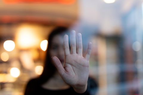 Frau und Hand vor Glasscheibe