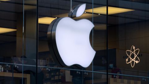 Das Logo von Apple - ein angebissener Apfel in weiß - leuchtet an einer Glasfassade