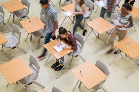Eine Schülerin schreibt ihre Abiturprüfung zu Ende. Alles anderen Schüler sind bereits bei der Abgabe ihrer Klausuren.