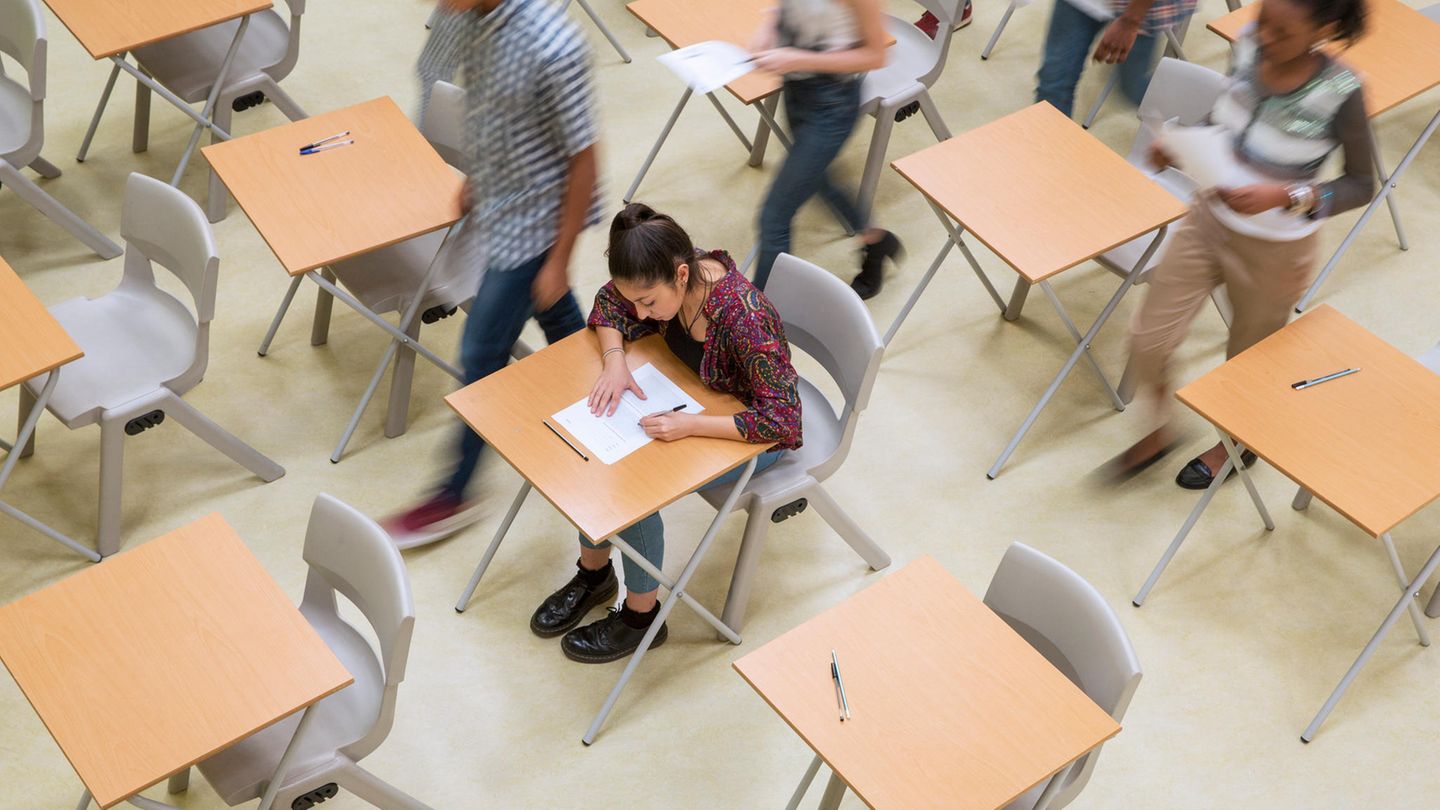 Eine Schülerin schreibt ihre Abiturprüfung zu Ende. Alles anderen Schüler sind bereits bei der Abgabe ihrer Klausuren.