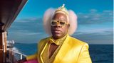 Clarence Thomas posiert in einem gelben Satin-Jacket, Pailletten-Oberteil und pinkem Tüll-Rock.