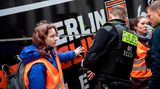 Polizisten lösen zwei Klimaaktivisten, die sich an einem Reisebus in Berlin festgeklebt haben. Nach Angaben der Bewegung haben sich ungefähr 800 Personen aus ganz Deutschland zum Protest in Berlin angemeldet. Die Störaktionen konzentrieren sich zunächst auf das Regierungsviertel, bevor sich die Aktivisten in der ganzen Stadt verteilen.