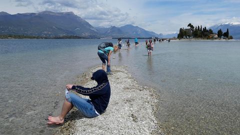 Ein Tourist hält seine Füße am Gardasee ins Wasser