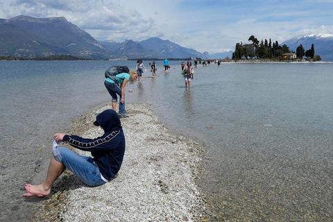 Ein Tourist hält seine Füße am Gardasee ins Wasser