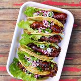 Chorizo-Tacos mit schwarzen Bohnen  Gut, dass es mittlerweile Soft-Tortilla-Fladen für Tacos vakuumiert im Supermarkt gibt. In der Kühltasche können sie unkompliziert mit auf die Reise gehen für leckere Grill-Tacos mit würziger Chorizo und cremigem Bohnenragout. Das lässt sich auch gut am Vortag zubereiten, es wird nach dem Aufwärmen nur besser.      Zutaten:  Für 4 Personen (bzw. 8 Tacos)  Fertig in 35 Minuten  - 1 Fleischtomate  - 1 Dose schwarze Bohnen (ca. 420 g EW, wahlweise Kidneybohnen oder weiße Bohnen)  - 2 rote Zwiebeln (Rotwein-)Essig Salz 4 EL Olivenöl  - 1 Knoblauchzehe  - 1 TL Tomatenmark  - 1–2 TL Ahornsirup oder Honig  - 200 ml Gemüsebrühe  - Chilisauce (z.B. Chipotles in Adobo oder Sriracha)  - 4 Römersalatblätter  - 1 Frühlingszwiebel  - 4 Chorizo-Würste  - 8 Tortilla-Fladen (ca. 10 cm Durchmesser)      Zubereitung:  1. Die Tomate würfeln. Die Bohnen abgießen und kalt abspülen, abtropfen lassen. Die Zwiebeln halbieren, pellen und fein würfeln. Die Hälfte davon mit Essig besprenkeln, salzen und beiseitestellen.  2. Die andere Hälfte der Zwiebeln in einer Pfanne in heißem Olivenöl glasig dünsten. Knoblauch pellen und fein gewürfelt mit den Tomaten zugeben. Tomatenmark und Ahornsirup unterrühren, die Bohnen zugeben. Brühe angießen und aufkochen. Offen 8–10 Minuten dicklich einkochen, mit Salz und Chilisauce würzen.  3. Salatblätter waschen und trockenschleudern. Frühlingszwiebel in feine Ringe schneiden und in kaltes Wasser legen. Die Chorizos längs halbieren und bei milder Hitze auf dem Grill oder auch in der beschichteten Pfanne ohne Fett 4–6 Minuten grillen oder braten.  4. Die Tortillas vor dem Erwärmen mit wenig Wasser anfeuchten und dann sekundenschnell auf dem Grill oder in einer Pfanne erwärmen. Mit je 1 Salatblatt, etwas Bohnenragout und 1⁄2 Chorizo füllen. Mit Essigzwiebeln und Frühlingszwiebeln getoppt servieren.