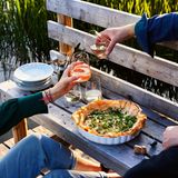 Tomaten-Ricotta-Tarte  Der Filo-Strudelteig rahmt knusprig die Füllung aus Ricotta, Kräuterfrischkäse und Tomaten. Nur die Erbsen dürfen erstmal nicht mit rein: Grün und knackig unterstützen sie auch optisch das Frühlingszwiebel- Dill-Topping. So geht Sommer, frisch aus dem Ofen!      Zutaten:  Für 4 Personen  Fertig in 30 Minuten (plus 35 Minuten Backzeit und 15 Minuten, um die fertige Tarte leicht abzukühlen)  - 2 Tomaten (250 g) Salz 2 Schalotten 1 Knoblauchzehe 250 g Ricotta  - 75 g Kräuterfrischkäse  - 50 g fein geriebener Parmesan  - 2 Eier (L)  - 1 TL fein geriebene unbehandelte Zitronenschale  - 1 Pkg. Filo- oder Yufka-Strudel- teigblätter (aus dem Frischeregal, ca. 250 g, 10 Blatt)  - Olivenöl  - 50 g TK-Erbsen  - 1 Frühlingszwiebel  - einige Dillspitzen (super auch Basili- kum, Kerbel und wenig Minze)      Zubereitung:  1. Die Tomaten vierteln, entkernen, das Fruchtfleisch in Würfel schneiden und salzen. Schalotten und Knoblauch halbieren, pellen und fein würfeln. Alles mit einem Schneebesen mit Ricotta, Kräuterfrischkäse, Parmesan und den Eiern gut verrühren. Zitronenschale unterrühren und mit Salz würzen.  2. 1 Teigblatt auf eine saubere Arbeitsfläche legen, dünn mit Oliven- öl bepinseln. Das nächste Blatt leicht versetzt darauflegen und ebenfalls dünn mit Öl bestreichen. So mit allen Teigblättern verfahren, nur das letzte Blatt nicht mehr mit Öl einpinseln.  3. Den Ofen auf 180 Grad schalten. Den Teigstapel vorsichtig in eine leicht geölte Back- oder Tarte-Form gleiten lassen und leicht an- drücken. Die Ränder der Teigblätter dürfen und sollen etwas über den Rand ragen oder abstehen.  4. Die Ricotta-Mischung einfüllen, die Tarte auf der ersten Schiene von unten 35 Minuten backen. Währenddessen die Erbsen 2–3 Minuten in Salzwasser kochen, kalt abschrecken und abtropfen. Frühlingszwiebel in Ringe schneiden und in kaltes Wasser legen.  5. Tarte aus dem Ofen nehmen und etwas abkühlen lassen. An einer Stelle mit einem Heber unter die Tarte fahren. Leicht anheben und auf ein bereitgestelltes Schneidbrett gleiten lassen. Die Frühlingszwiebelringe abtropfen und mit ein paar Tropfen Öl und den Erbsen mischen, leicht salzen und auf der Tarte verteilen. Mit frisch gezupftem Dill bestreut servieren.