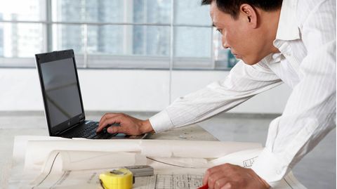 Forsa-Umfrage: Ein Mann beugt sich über den Schreibtisch und tippt auf dem Laptop