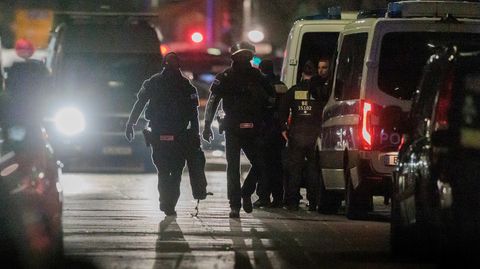 Polizisten gehen zu den Einsatzfahrzeugen nach der Beendigung einer Geiselnahme in einem Geschäft an der Keithstraße in Berlin