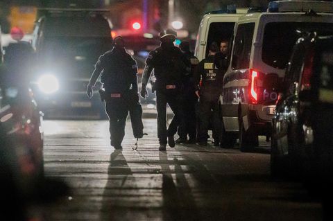 Polizisten gehen zu den Einsatzfahrzeugen nach der Beendigung einer Geiselnahme in einem Geschäft an der Keithstraße in Berlin