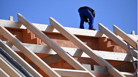 Ein Arbeiter ist auf dem Dach eines Rohbaus tätig