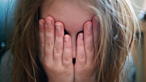 Depression bei Kindern: Ein junges Mädchen hält sich die Hände vor ihr Gesicht