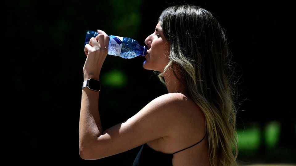 Eine Frau trinkt Wasser, um sich bei den hohen Temperaturen in Sevilla abzukühlen,