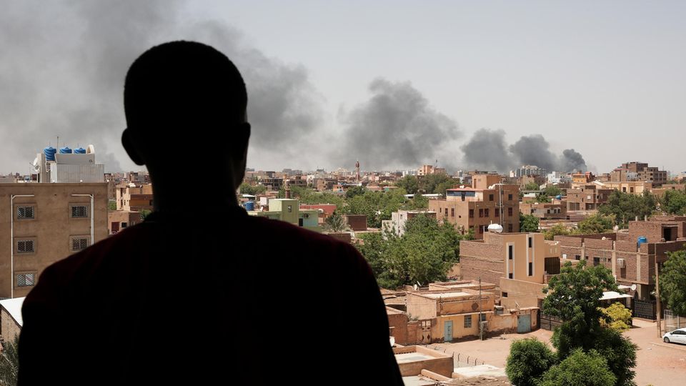 Ein Mann blickt auf eine Rauchsäule im umkämpften Khartum