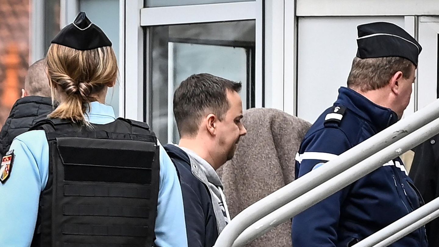Zwischen blau uniformierten Polizistinnen und Polizisten geht ein Mensch unter einer grau-braunen Decke