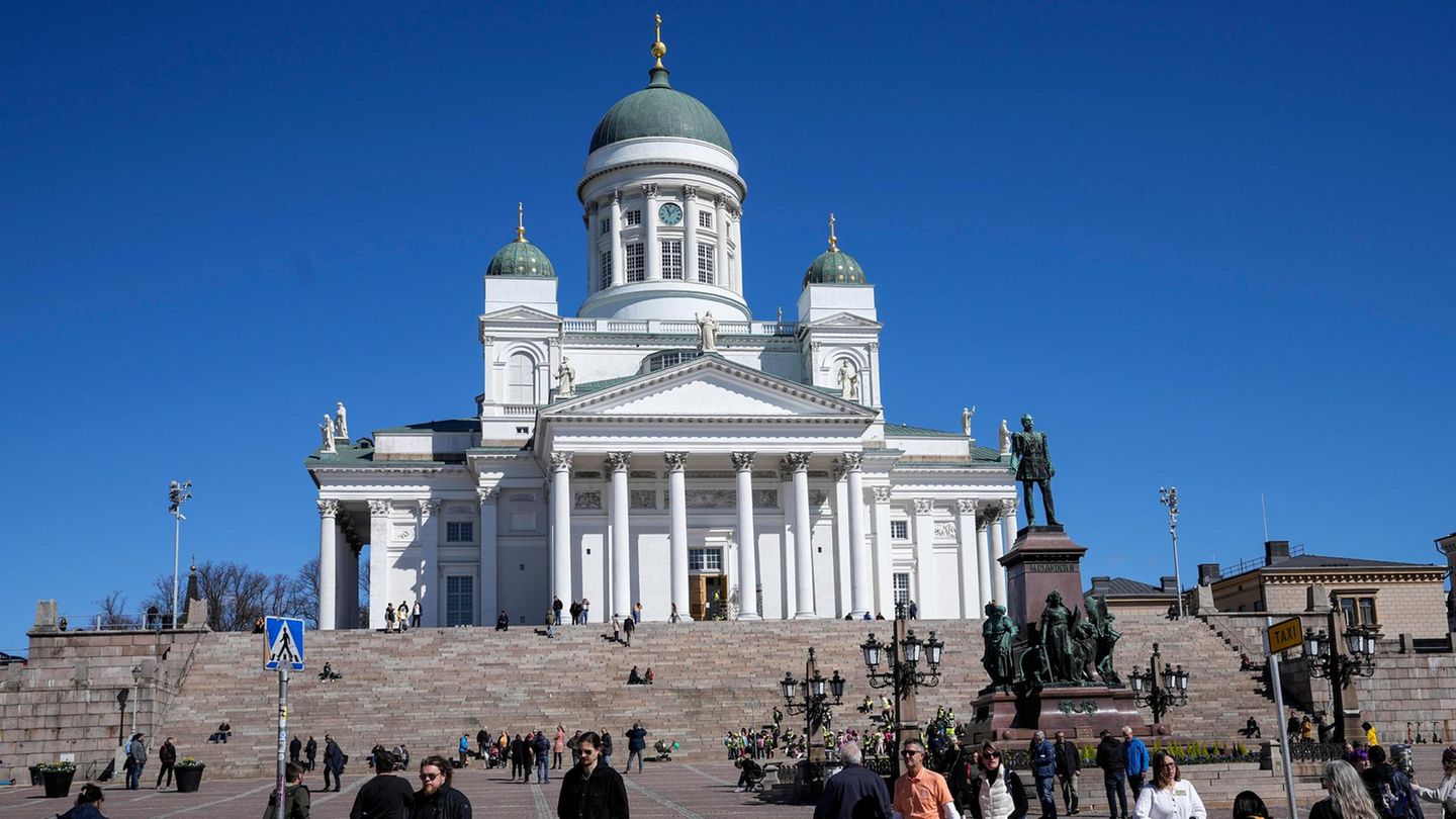 Menschen gehen vor dem Dom von Helsinki, Finnland unter blauem Himmel im Stadtzentrum