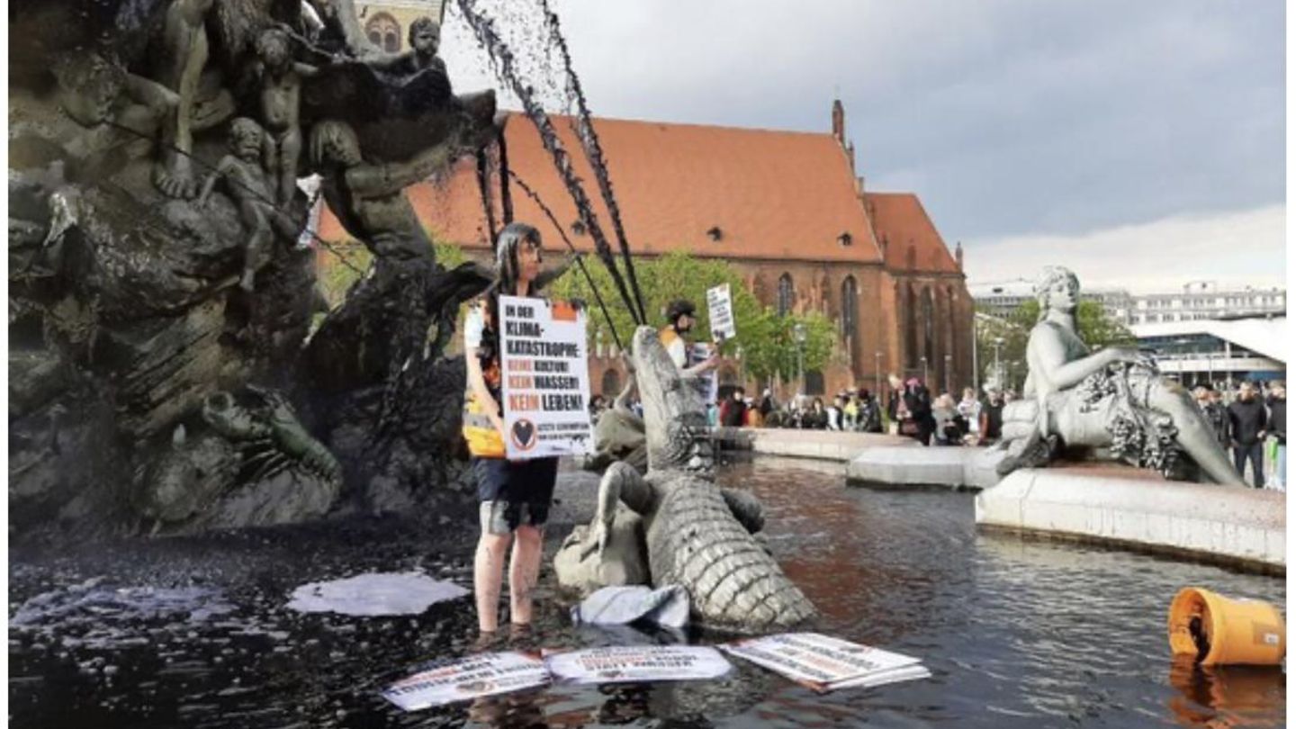 Im Märchenbrunnen steht die Aktivistin Judith Beadle mit einem Schild. Darauf steht: "In der Klimakatastrophe: Keine Kultur! Kein Wasser! Kein Leben!" Um ihre Nachricht Ausdruck zu verleihen, haben die Aktivisten der Letzten Generation das Brunnenwasser mit Pulver schwarz gefärbt. Einige überschütteten sich laut Mitteilung mit schwarzem Leim – ein Symbol für Erdöl.