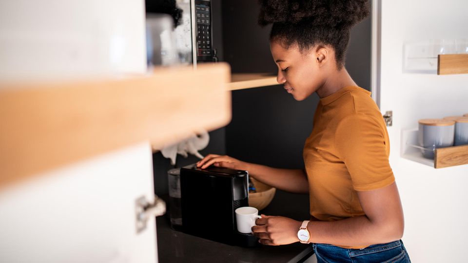 Eine Fraut steht an einer Kaffeemaschine.
