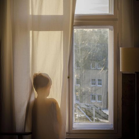 Kind steht am Fenster und schaut hinaus