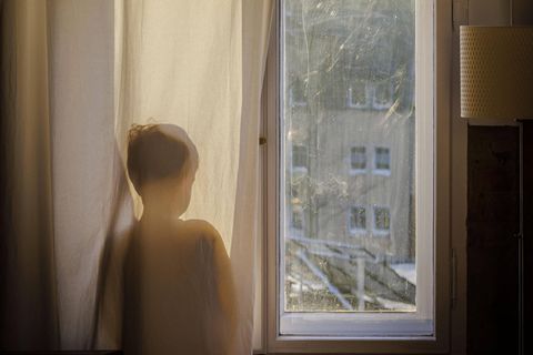 Kind steht am Fenster und schaut hinaus
