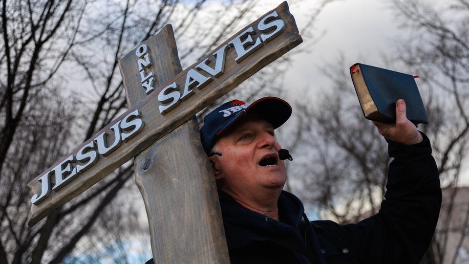 Ein Mann protestiert mit einem Kreuz und einer Bible beim "March for Life" in Washington D.C., USA