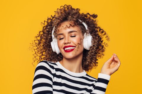 Bose Brand Week bei Amazon: Eine Frau lächelt, weil sie Musik über Kopfhörer genießt