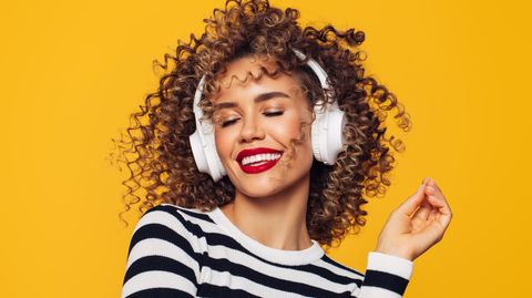 Bose Brand Week bei Amazon: Eine Frau lächelt, weil sie Musik über Kopfhörer genießt