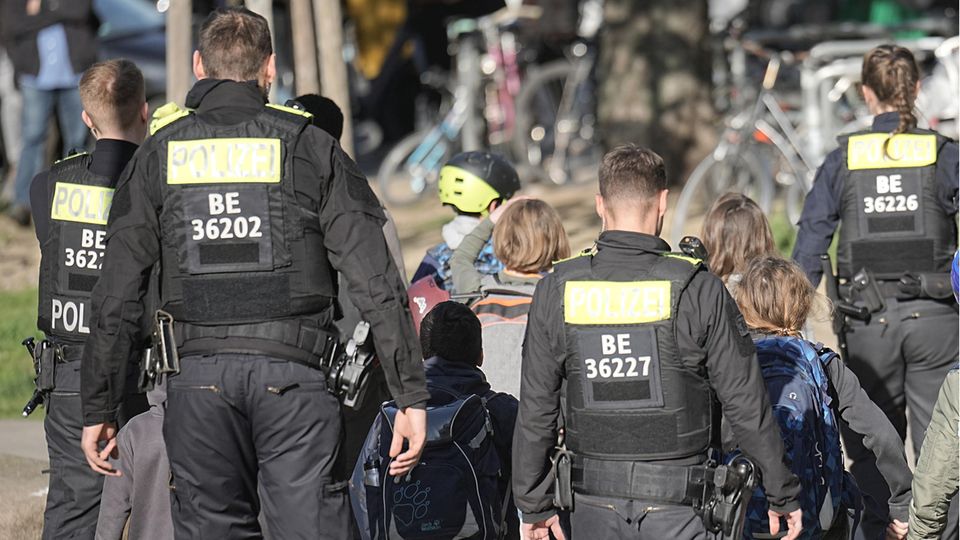 Polizisten geleiten Kinder von einer Schule in Berlin-Neukölln weg