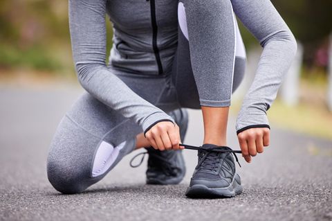 Eine Frau schnürt sich draußen die Schuhe