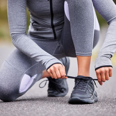 Eine Frau schnürt sich draußen die Schuhe
