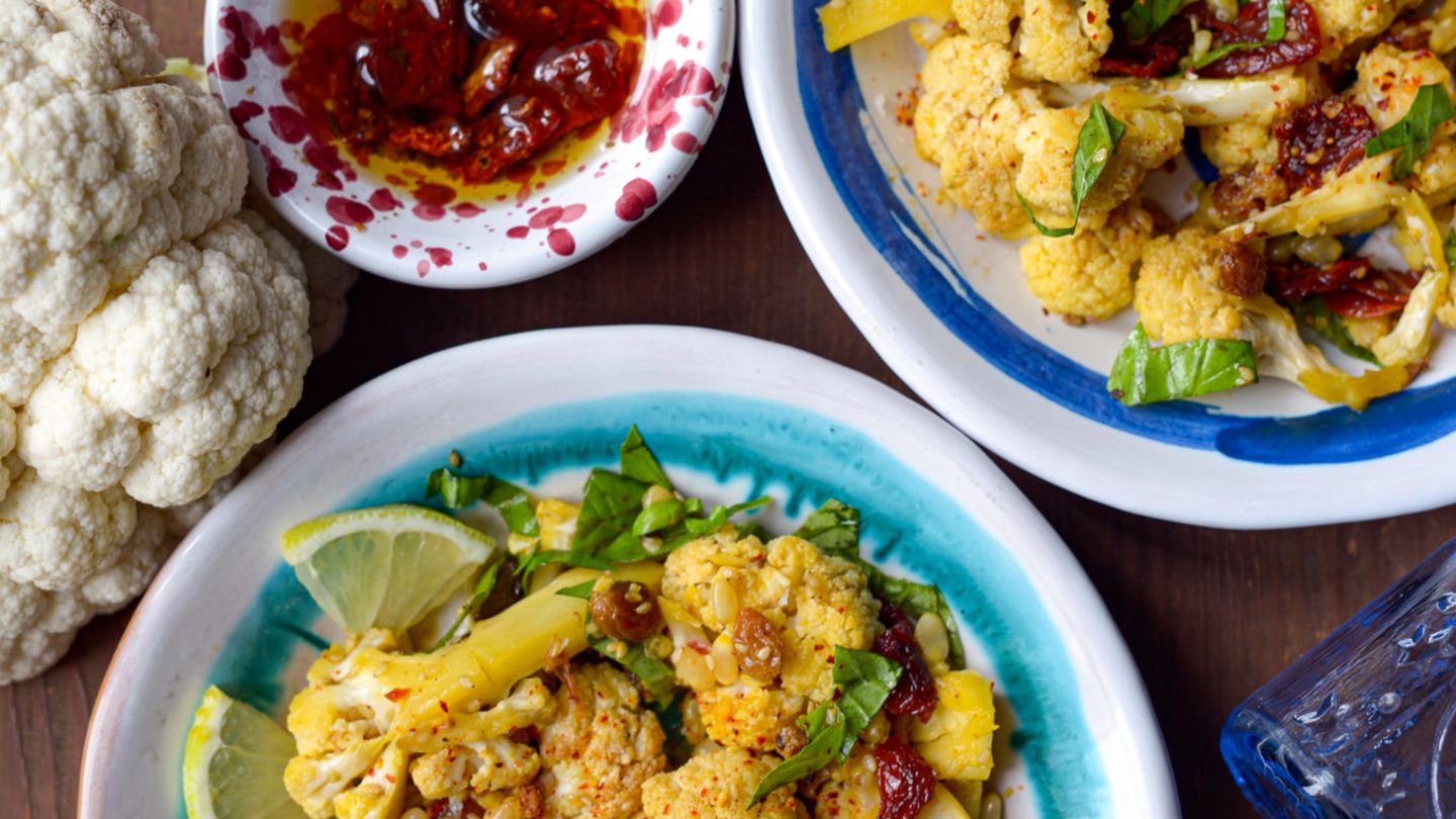 Insalata di cavolfiore alla siciliana (Sizilianischer Blumenkohlsalat)  Für 4 Personen  Zubereitungszeit 15 Minuten, plus Backzeit 35 Minuten      Zutaten:  - 1 kg Blumenkohl  - Meersalz  - 80 g Rosinen  - 1 g Safran  - 80 ml natives Olivenöl extra  - 30 g Sesam  - 40 g Pinienkerne, ohne Fett geröstet  - 2 Knoblauchzehen, in Streifen geschnitten  - 5 getrocknete, in Öl eingelegte Kirschtomaten  - Saft und Abrieb von 1 Bio-Zitrone  - 1 EL Marrocan-Gewürz (z. B. von El Puente, ersatzweise eine Mischung aus Ingwer, schwarzem Pfeffer, braunem Kandiszucker, Kreuzkümmel, Zimt, Koriander, Paprika, Minze, Chili, Kurkuma und Rosenblüten)  - 2 Handvoll Basilikum, grob gehackt      Zubereitung:  1. Den Blumenkohl putzen und in kleine Röschen teilen. In einen Topf mit kochendem Salzwasser geben und in etwa 5–7 Minuten sehr bissfest garen. Den Blumenkohl abseihen. Die Rosinen mit dem Safran in eine Schüssel geben und mit 200 ml kochend heißem Wasser übergießen.  2. Den Ofen auf 160 °C Umluft vorheizen. Den Blumenkohl zusammen mit dem Olivenöl, dem Sesam, den Pinienkernen, dem Knoblauch, den Tomaten, dem Zitronensaft und -abrieb und dem Marrocan-Gewürz in eine große Schüssel geben und alles gut miteinander vermischen. Mit Salz abschmecken und auf einem mit Backpapier ausgelegten Backblech verteilen. Den Blumenkohl auf der zweiten Schiene von oben 25 Minuten rösten. Ab und an umrühren. Nach der Röstzeit die Rosinen mit dem Safranwasser dazugeben, gut vermischen und weitere 10 Minuten garen.  3. Aus dem Ofen nehmen, auf Teller verteilen, mit dem Basilikum bestreuen, nach Belieben etwas Olivenöl darüberträufeln und servieren.