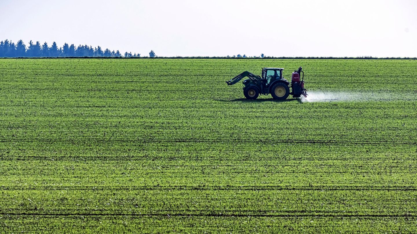 Ein Landwirt bringt mit seinem Traktor Düngemittel auf einem Feld aus